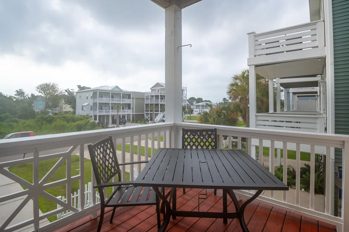 An inviting patio table sits surrounded by lush greenery, offering a scenic view of neighboring homes. The setup suggests a perfect spot for morning coffee or evening cocktails, with enough space for small gatherings and al fresco meals.