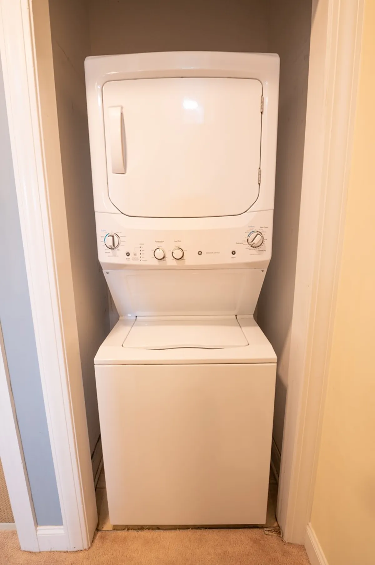 An in-hall laundry area featuring a stacked washer and dryer, offering practical convenience for families during their stay.